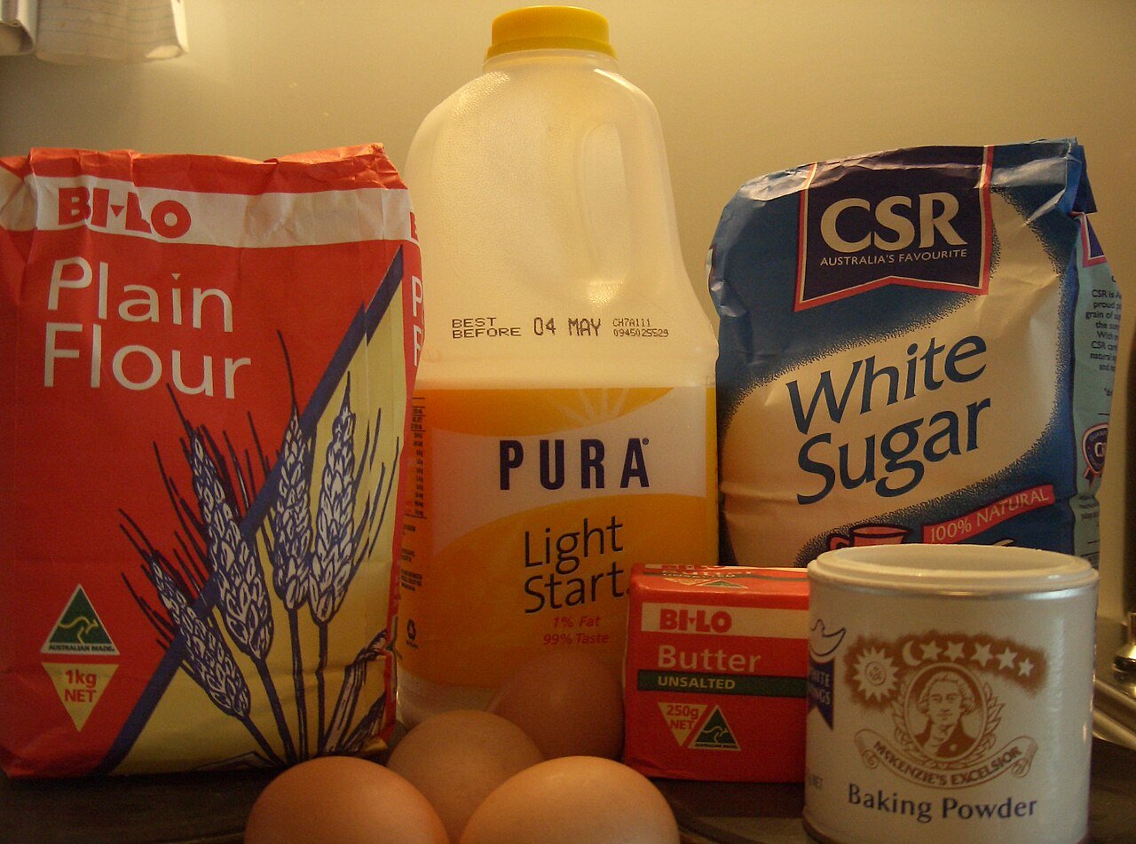 Flour, eggs, milk, butter, sugar and baking powder laid out for a butter cake